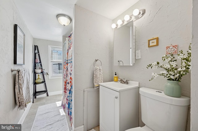 full bathroom with vanity, baseboards, curtained shower, toilet, and a textured wall