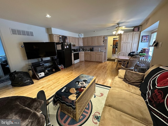 living area with visible vents, light wood-type flooring, and a ceiling fan