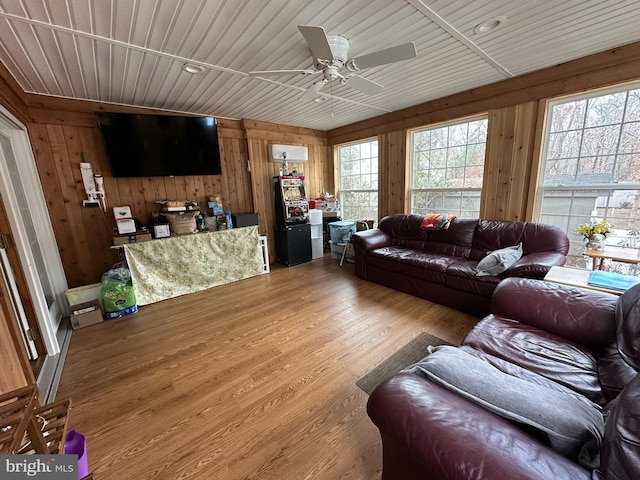 living area with wooden walls, wood ceiling, ceiling fan, and wood finished floors