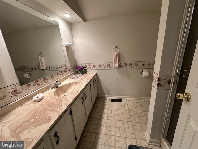 full bath with visible vents, vanity, brick floor, and baseboards