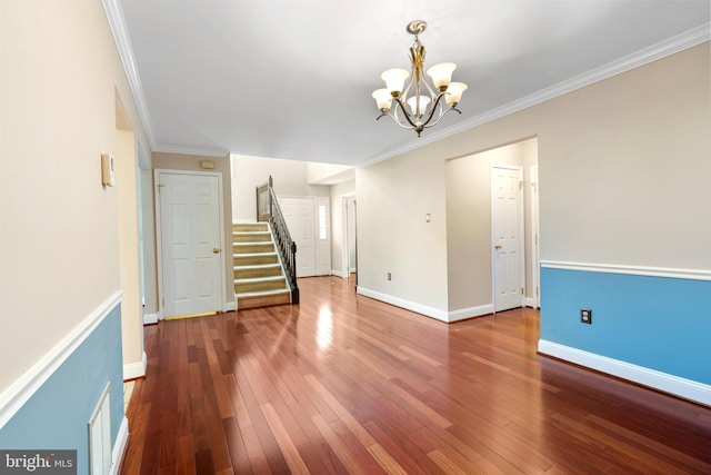 unfurnished room with stairway, baseboards, an inviting chandelier, wood-type flooring, and crown molding