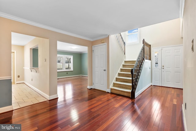 foyer entrance with hardwood / wood-style floors, stairs, a wealth of natural light, and ornamental molding