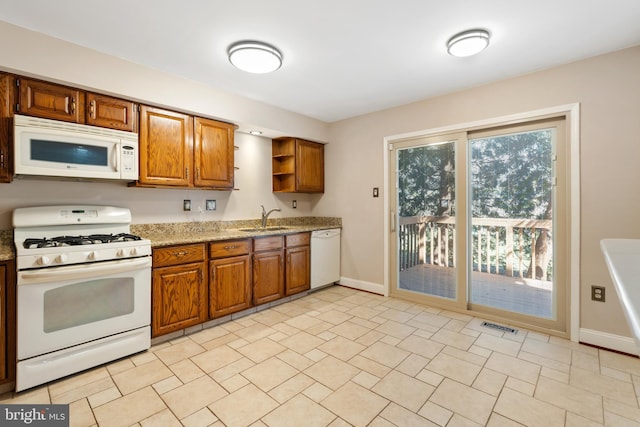 kitchen with white appliances, brown cabinetry, visible vents, open shelves, and a sink