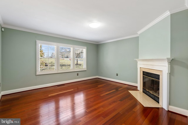 unfurnished living room with a fireplace with flush hearth, crown molding, baseboards, and hardwood / wood-style floors