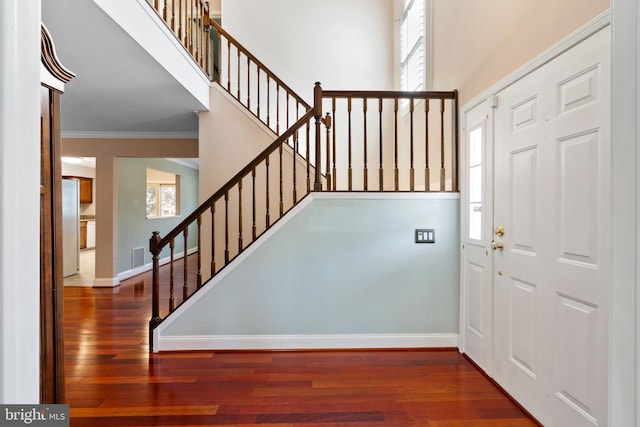 entryway with ornamental molding, hardwood / wood-style floors, a high ceiling, baseboards, and stairs