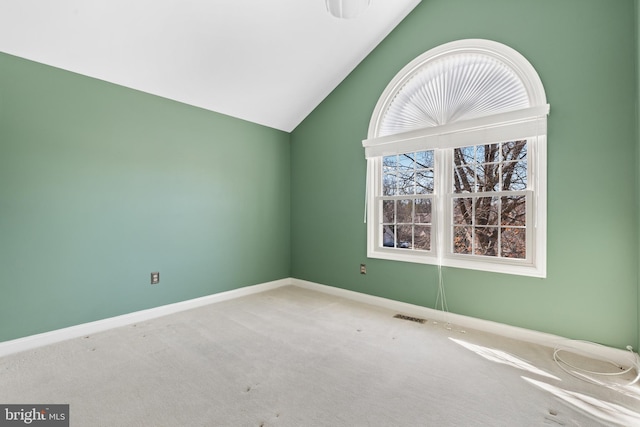 carpeted spare room with visible vents, baseboards, and lofted ceiling