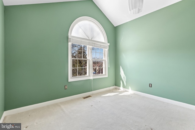 spare room with lofted ceiling, visible vents, baseboards, and carpet floors