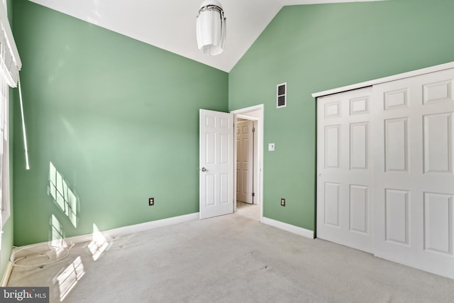 unfurnished bedroom featuring a closet, baseboards, high vaulted ceiling, and carpet