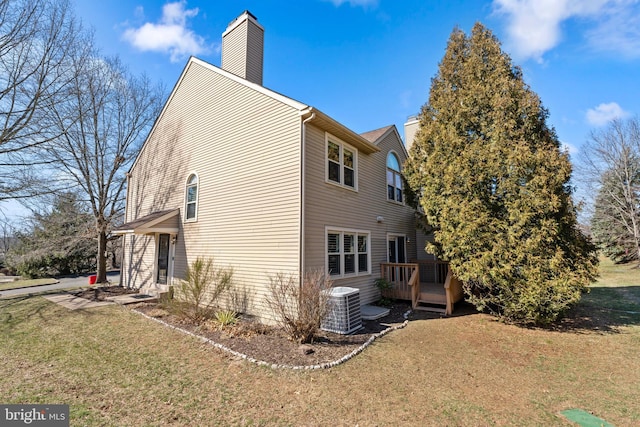 view of side of property with a wooden deck, a lawn, central AC unit, and a chimney