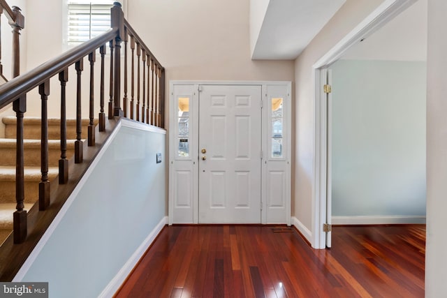 foyer featuring baseboards, a healthy amount of sunlight, stairs, and hardwood / wood-style flooring