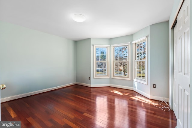 unfurnished bedroom featuring hardwood / wood-style flooring, baseboards, and a closet