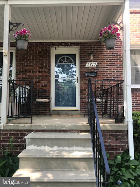 view of exterior entry with brick siding and a porch