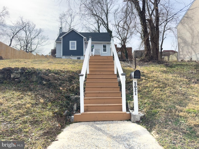 view of front facade with stairs, fence, and a chimney