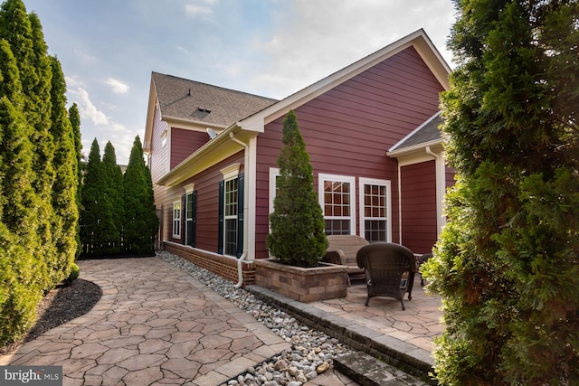 back of house with a shingled roof and a patio