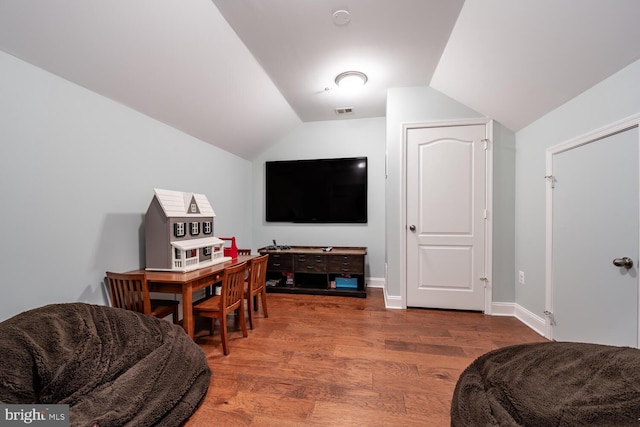 interior space featuring visible vents, baseboards, wood finished floors, and vaulted ceiling