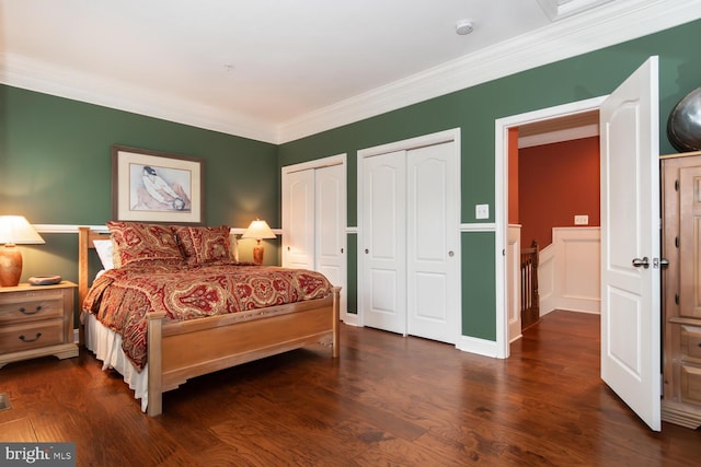 bedroom with dark wood-style floors, multiple closets, and ornamental molding