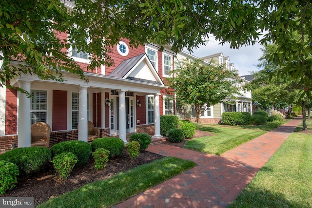 view of front of home with brick siding, covered porch, and a front lawn