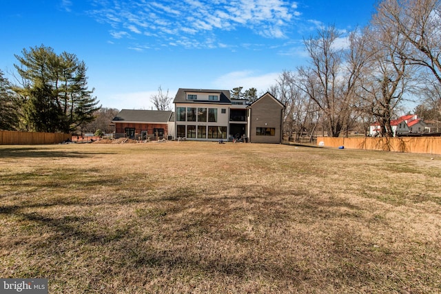 back of house with fence, a lawn, and a sunroom