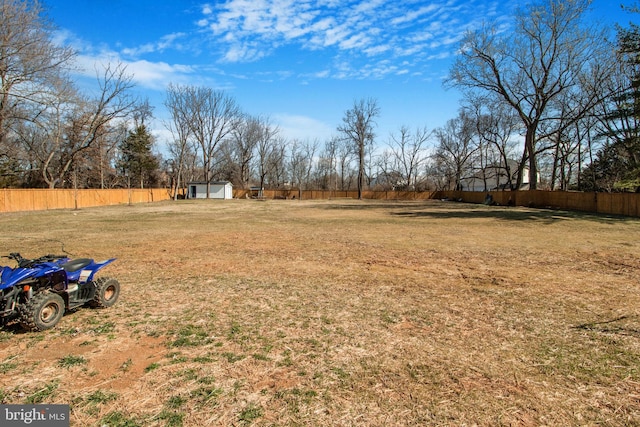 view of yard featuring an outbuilding, a shed, and fence