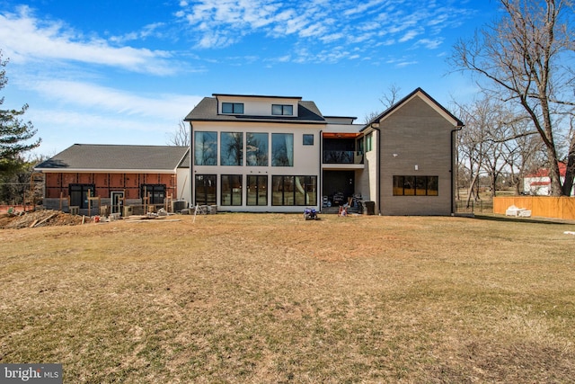 back of property featuring a yard, fence, and a sunroom