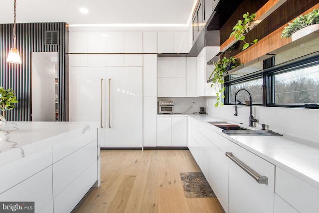 kitchen with light wood-type flooring, modern cabinets, open shelves, a sink, and white cabinets