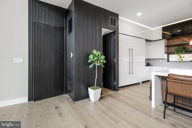 kitchen featuring a breakfast bar area, light countertops, light wood-style flooring, white cabinetry, and modern cabinets