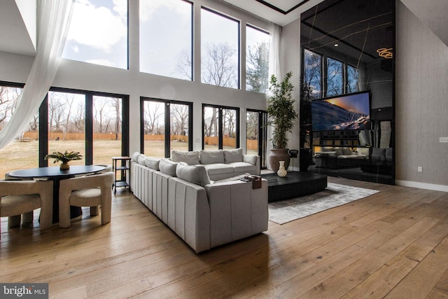 living area featuring a high ceiling, light wood-style flooring, and baseboards