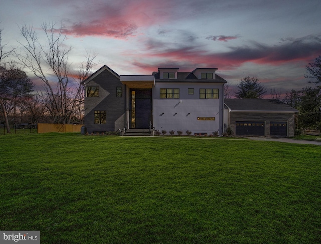 view of front of property featuring a garage, driveway, a front lawn, and fence