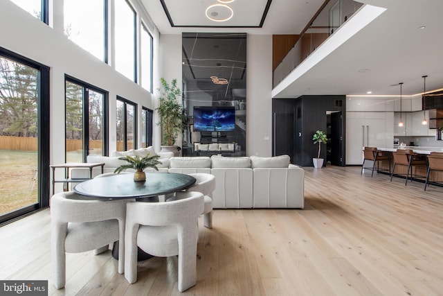 dining room with light wood-style flooring and a towering ceiling