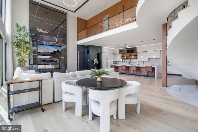 dining space with light wood-style floors and a towering ceiling