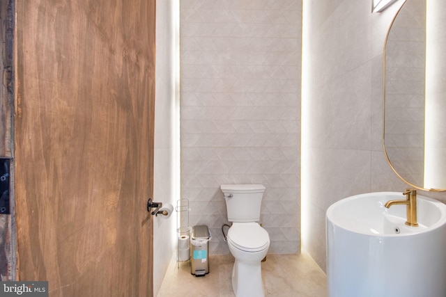 bathroom featuring tile patterned flooring, tile walls, and toilet