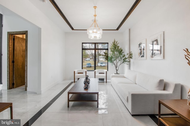 living area featuring an inviting chandelier, baseboards, and a raised ceiling