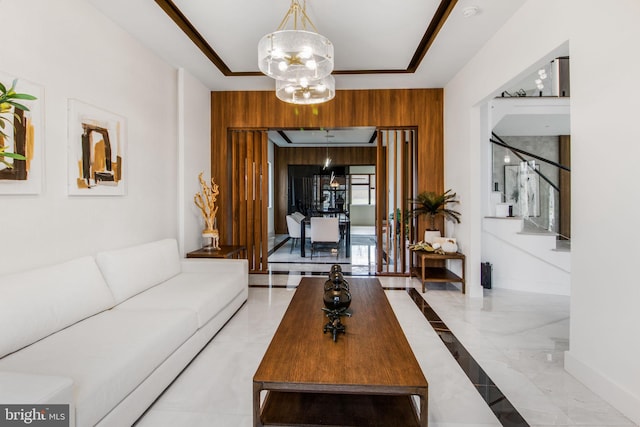 living area featuring baseboards, wooden walls, an inviting chandelier, and stairs