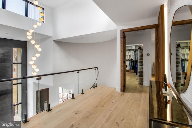 corridor with an upstairs landing, a high ceiling, and hardwood / wood-style flooring