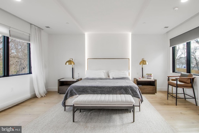 bedroom featuring light wood-style flooring, visible vents, and baseboards