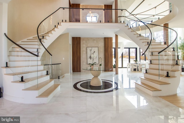 foyer entrance featuring stairs, a high ceiling, and marble finish floor