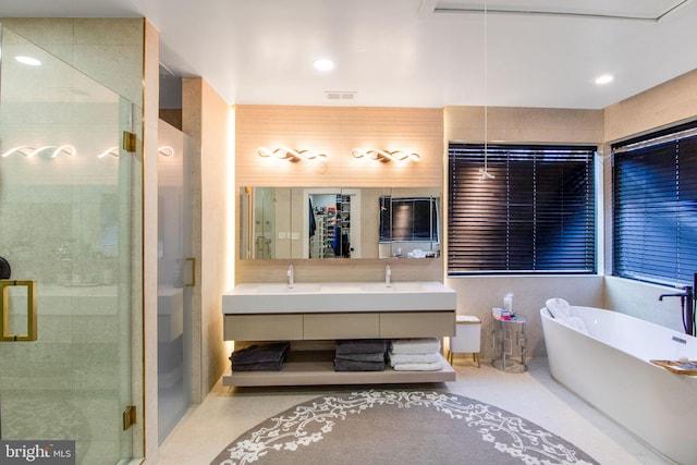 full bath with visible vents, a shower stall, double vanity, a freestanding tub, and a sink