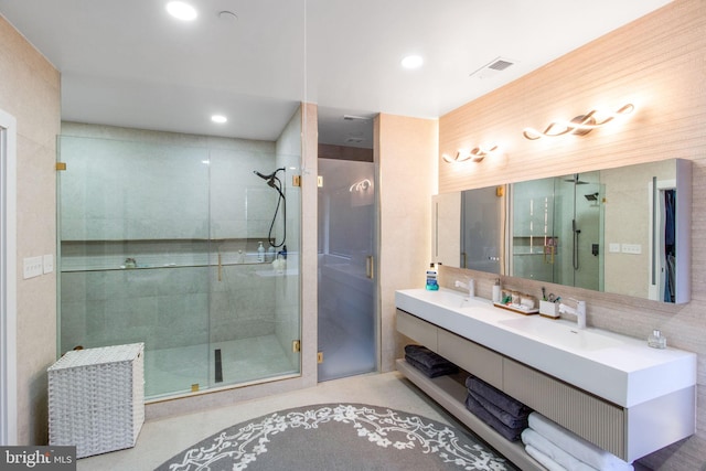 bathroom featuring double vanity, visible vents, a shower stall, and a sink