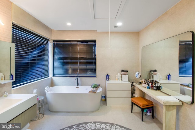 full bath featuring vanity, a soaking tub, recessed lighting, and tile walls