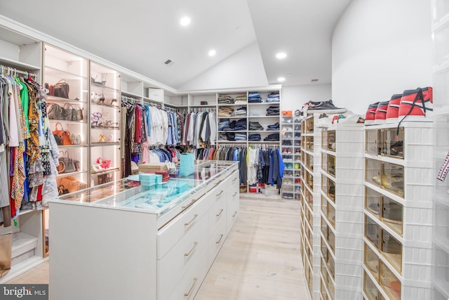 walk in closet with light wood-style floors and vaulted ceiling