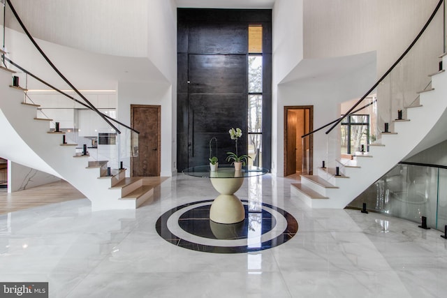 foyer with stairway, a high ceiling, and marble finish floor