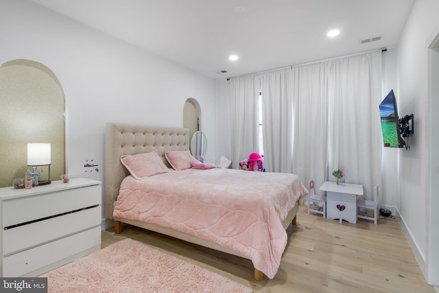 bedroom with arched walkways, visible vents, recessed lighting, and light wood-type flooring