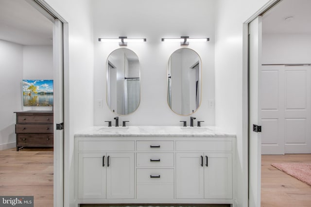 full bathroom with double vanity, wood finished floors, and a sink