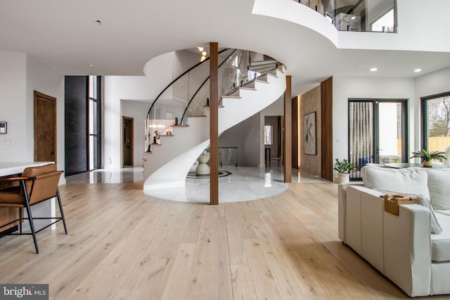 foyer with stairway, light wood-style floors, and a high ceiling