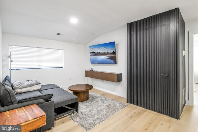 living area featuring vaulted ceiling, visible vents, and wood finished floors