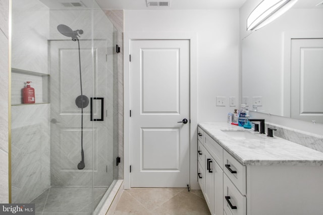 bathroom with a marble finish shower, visible vents, tile patterned floors, and vanity