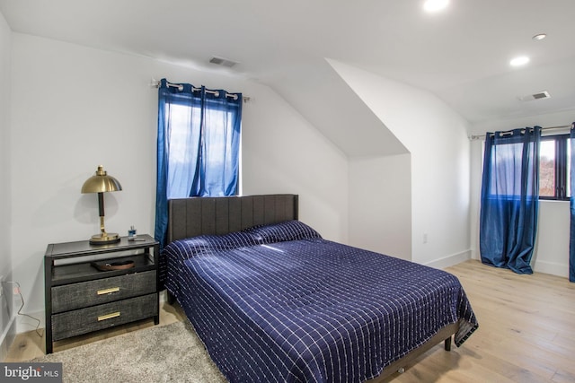 bedroom featuring visible vents, baseboards, lofted ceiling, and wood finished floors