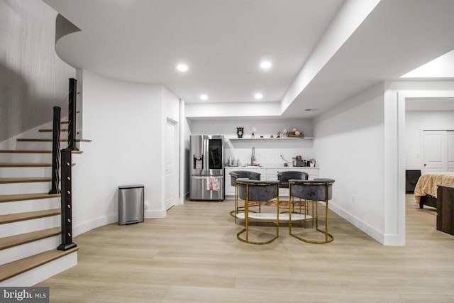 bar featuring light wood finished floors, baseboards, stairway, recessed lighting, and stainless steel fridge