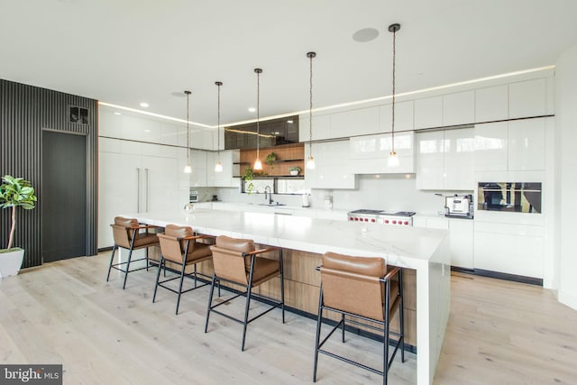 kitchen with light wood finished floors, stove, white cabinets, modern cabinets, and a sink