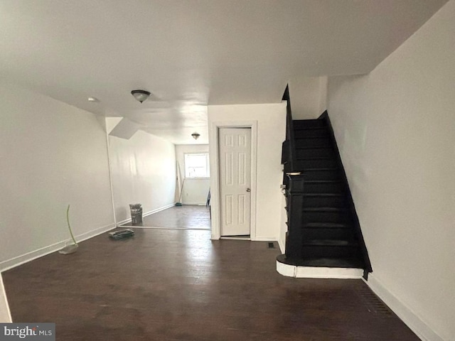 unfurnished living room featuring stairs, wood finished floors, and baseboards